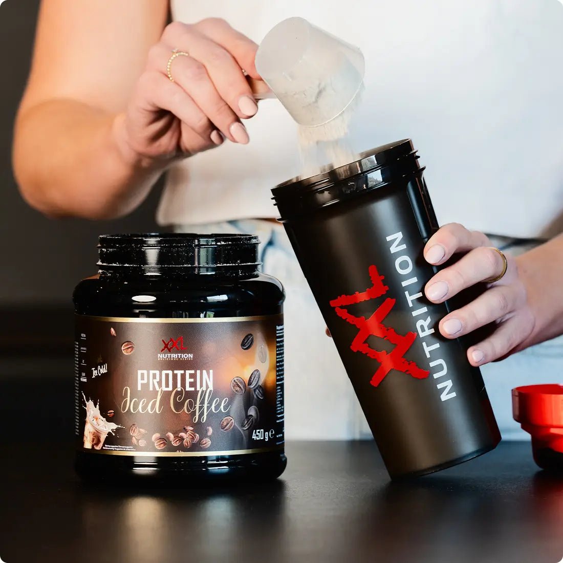 XXL Nutrition Protein Iced Coffee, erfrischendes Kaffee-Getränk mit Protein, in einer transparenten Flasche mit Kaffee und Eiswürfeln